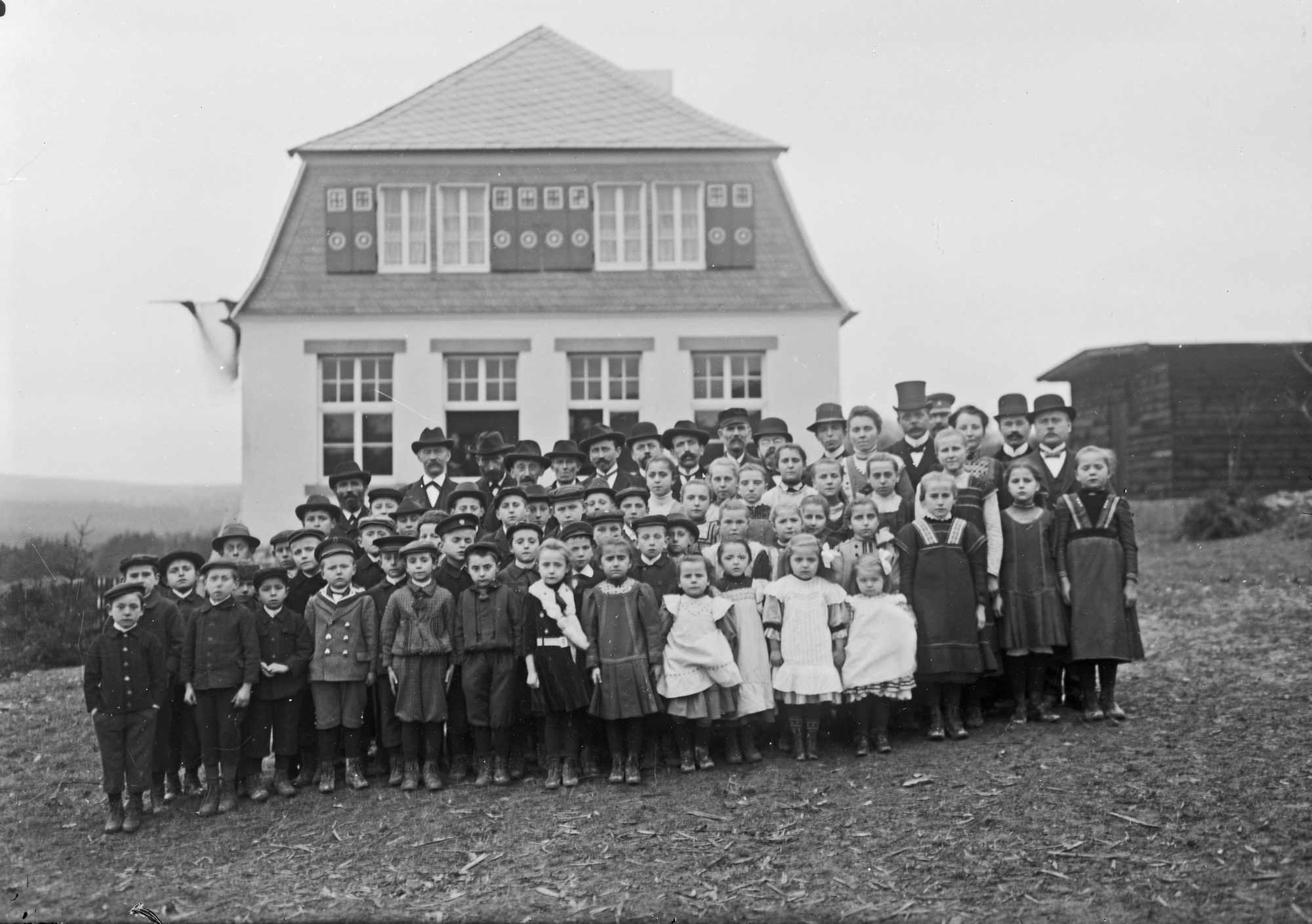 Schulklasse vor einer Dorfschule